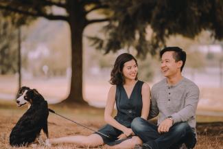 Happy couple sitting in a park with their dog